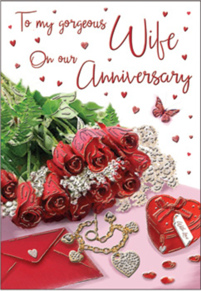 The image captures an anniversary card styled as a rich, emotive still life, evoking the atmosphere of a carefully planned celebration in Somers Town. At the centre, a bouquet-style cluster of classic red roses takes pride of place, each blossom full and voluptuous, with petals unfolding in plush, velvety layers. Their deep crimson colour feels both dramatic and reassuring, like a symbol of love that has weathered many seasons together. Intertwined with the roses are strands of lush greenery, ferns, and fine foliage that soften the overall look, bringing a sense of nature's abundance and echoing the calm greenery found in nearby parks and courtyards. Beneath and around the blooms, whisper-thin touches of lace or delicate filigree patterns appear, their intricate textures adding elegance without overwhelming the floral focus. Resting close by is a vivid red box, most likely for jewellery, its clean, structured lines and smooth surface suggesting something precious kept inside-perhaps an anniversary pendant or ring. Alongside it, hints of a jewellery set glimmer faintly: a small necklace, earrings, or bracelet, their metallic surfaces catching the light in tiny flashes of gold and silver. Scattered heart motifs and tiny embellishments drift across the card like shared memories, some more defined, others subtle and soft-edged. The background remains warm and gently blurred, allowing the roses and keepsakes to stand out clearly while maintaining an intimate, cocooning feel. Everything from the scripted message, partly visible in graceful lettering, to the interplay of textures-velvet petals, polished metal, and smooth card stock-conveys the warmth of an embrace. It feels like a visual tribute to the milestones couples celebrate together near St Pancras and along the quiet streets of Somers Town.